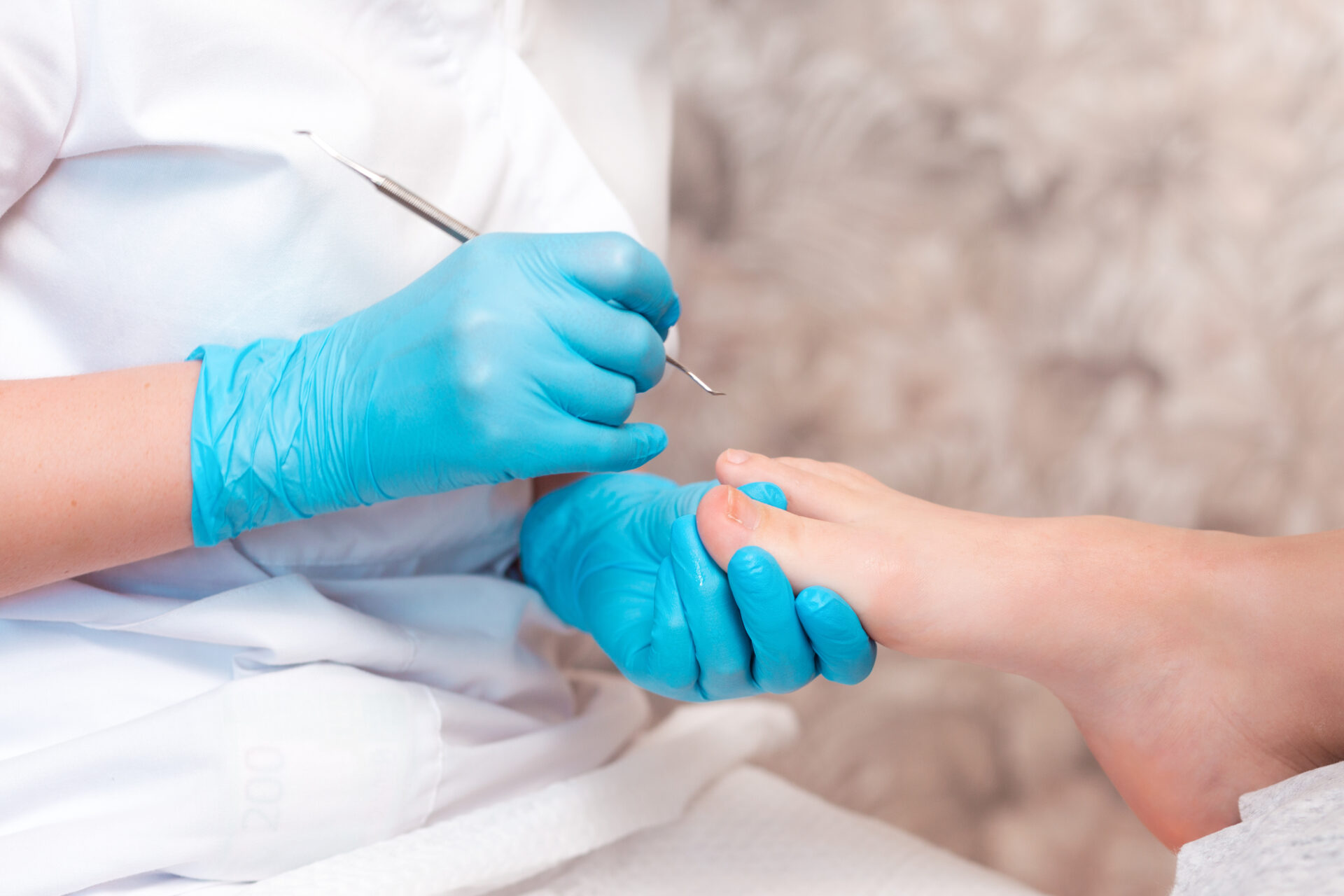 Pedicurist does a pedicure for the client's foot, cleaning the nails with a double-sided curette. Close up. The concept of chiropody and podology.