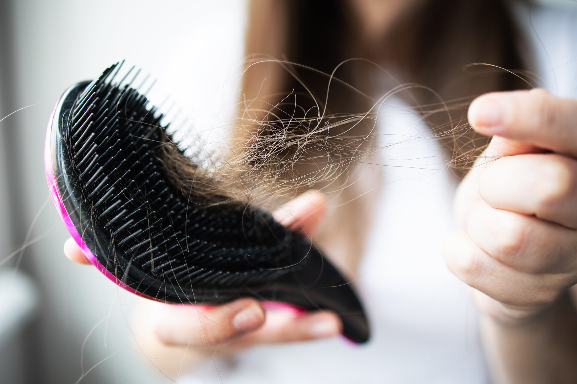 Focus no face a woman holding a black comb in her hands, clearing her of fallen hair after combing. Concept: hair problems, stress and depression, the effect of chemotherapy and radiation in cancer