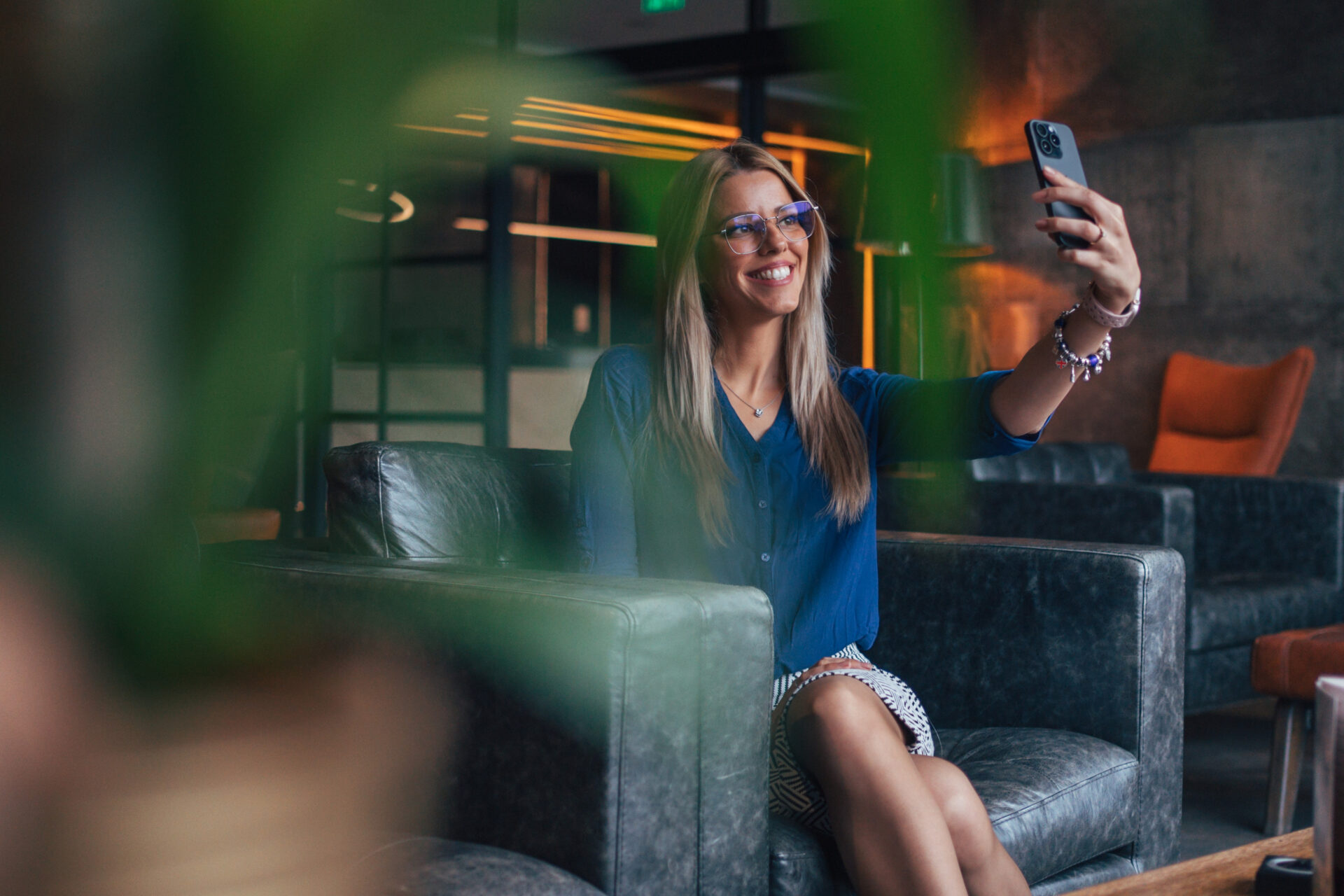 Młoda bizneswoman o blond włosach i w okularach robi sobie selfie smartfonem