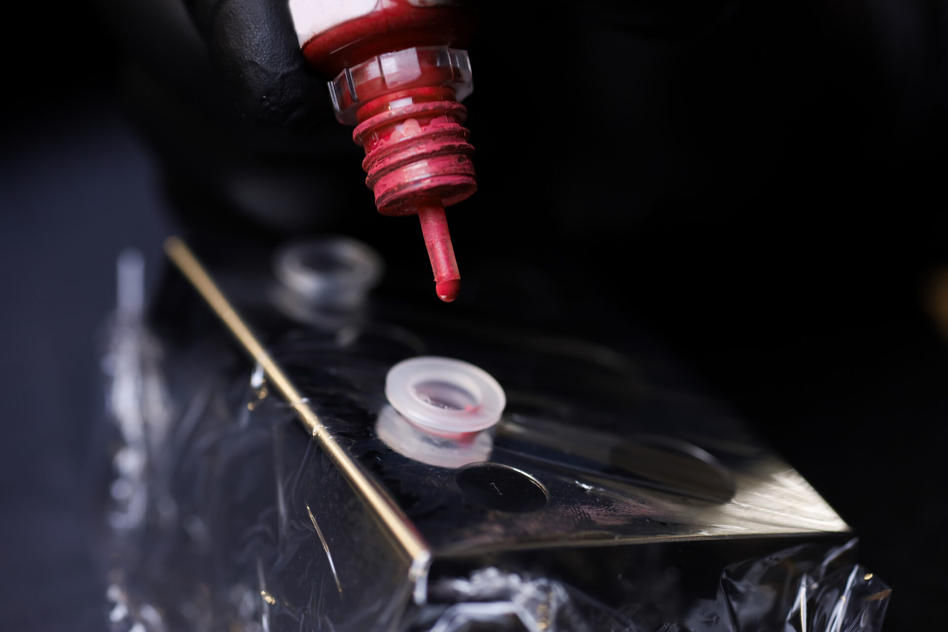 zbliżenie na mistrza wlewającego pigmenty ze słoika do plastikowej kapsułki w celu wymieszania pigmentu do tatuażu