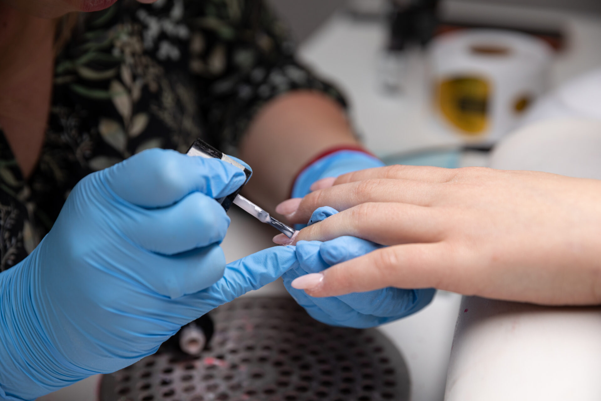 In a professional salon setting, a skilled nail technician artfully applies gel polish onto beautifully manicured nails