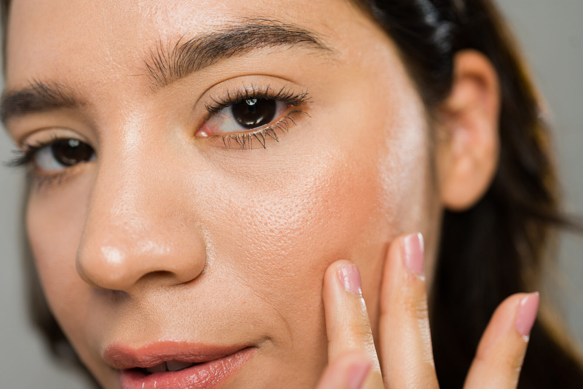 Młoda kobieta nakłada krem nawilżający na twarz, podkreślając znaczenie pielęgnacji skóry dla uzyskania zdrowej i promiennej cery