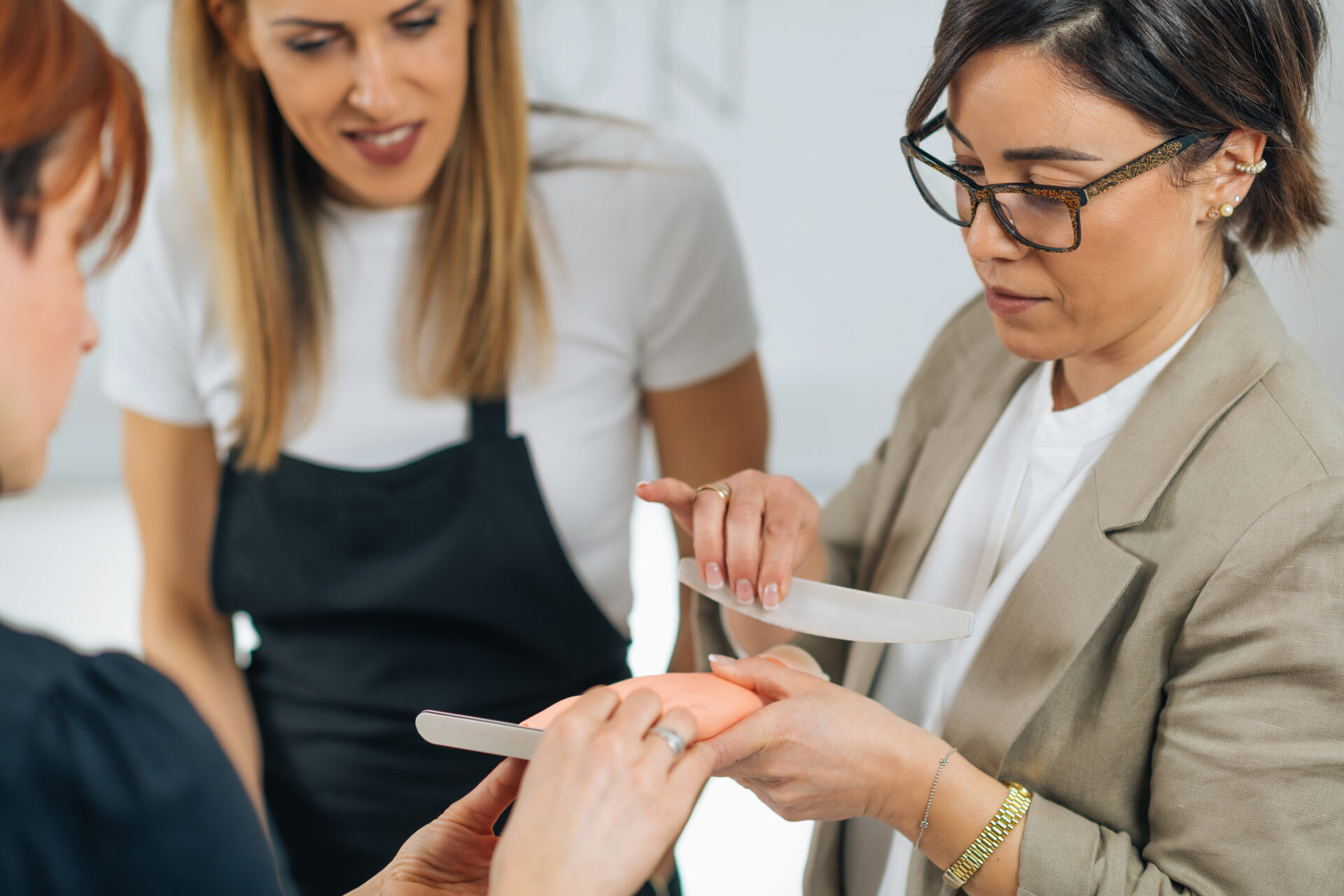 Ćwiczenia z manicure przy użyciu sztucznych paznokci akrylowych na manekinowej dłoni szkoleniowej w centrum kosmetycznym