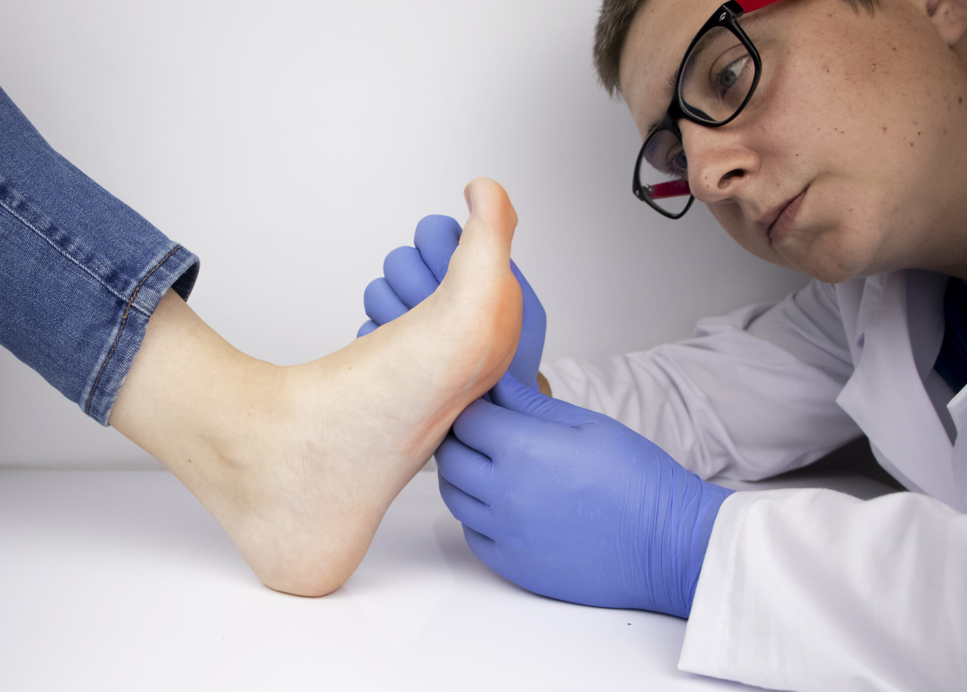 Leczenie grzybic i pomoc dla pacjentów cierpiących na choroby grzybicze. Dermatolog bada paznokieć u nogi dotknięty grzybicą.
