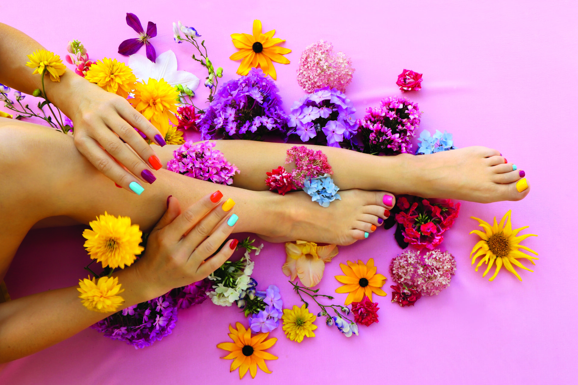 Wielobarwny manicure i pedicure na paznokciach o kwadratowym kształcie z różnymi motywami kwiatowymi.