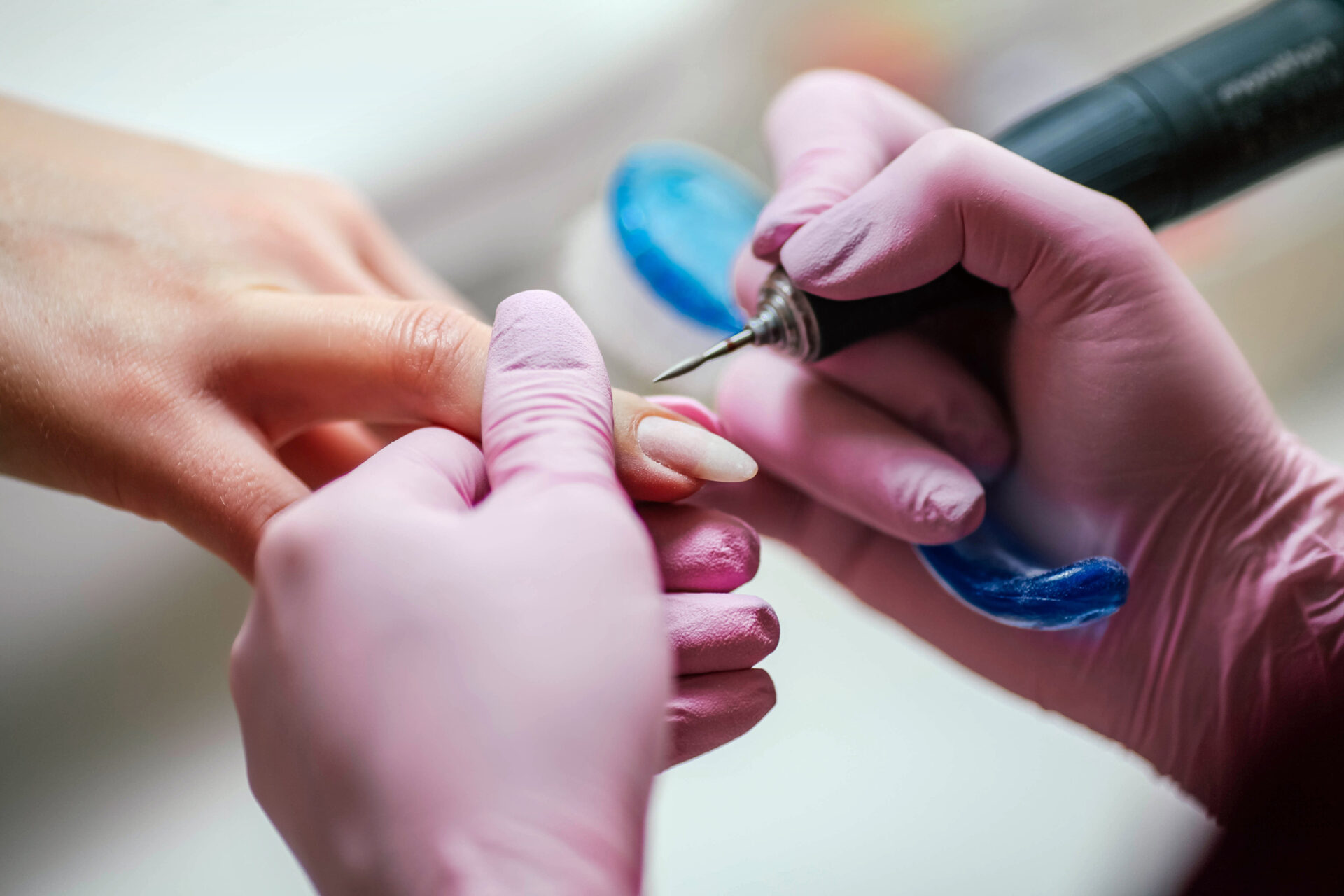 Kobieta używa elektrycznej pilniczki do paznokci w salonie kosmetycznym. Zbliżenie na proces wykonywania manicure.