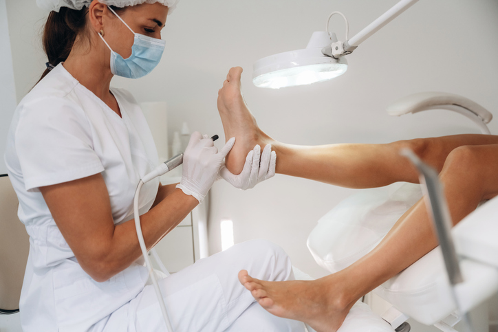View from the side, doing peeling. Podiatrist with client in clinic.