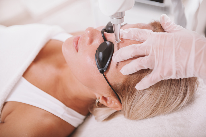 Close up of a mature woman getting her eyebrow tattoo removed with laser by professional cosmetologist