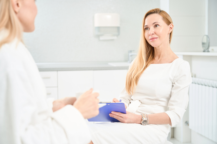 Atrakcyjna lekarka medycyny ogólnej, uważnie słuchająca swojej pacjentki, która zgłosiła się do kliniki medycyny estetycznej w celu odmłodzenia i wzmocnienia skóry oraz ciała