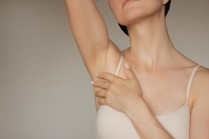 photo of a pretty young Caucasian woman in beige underwear gently touching her smooth body after epilation of armpits. Shaving and epilation of the body.