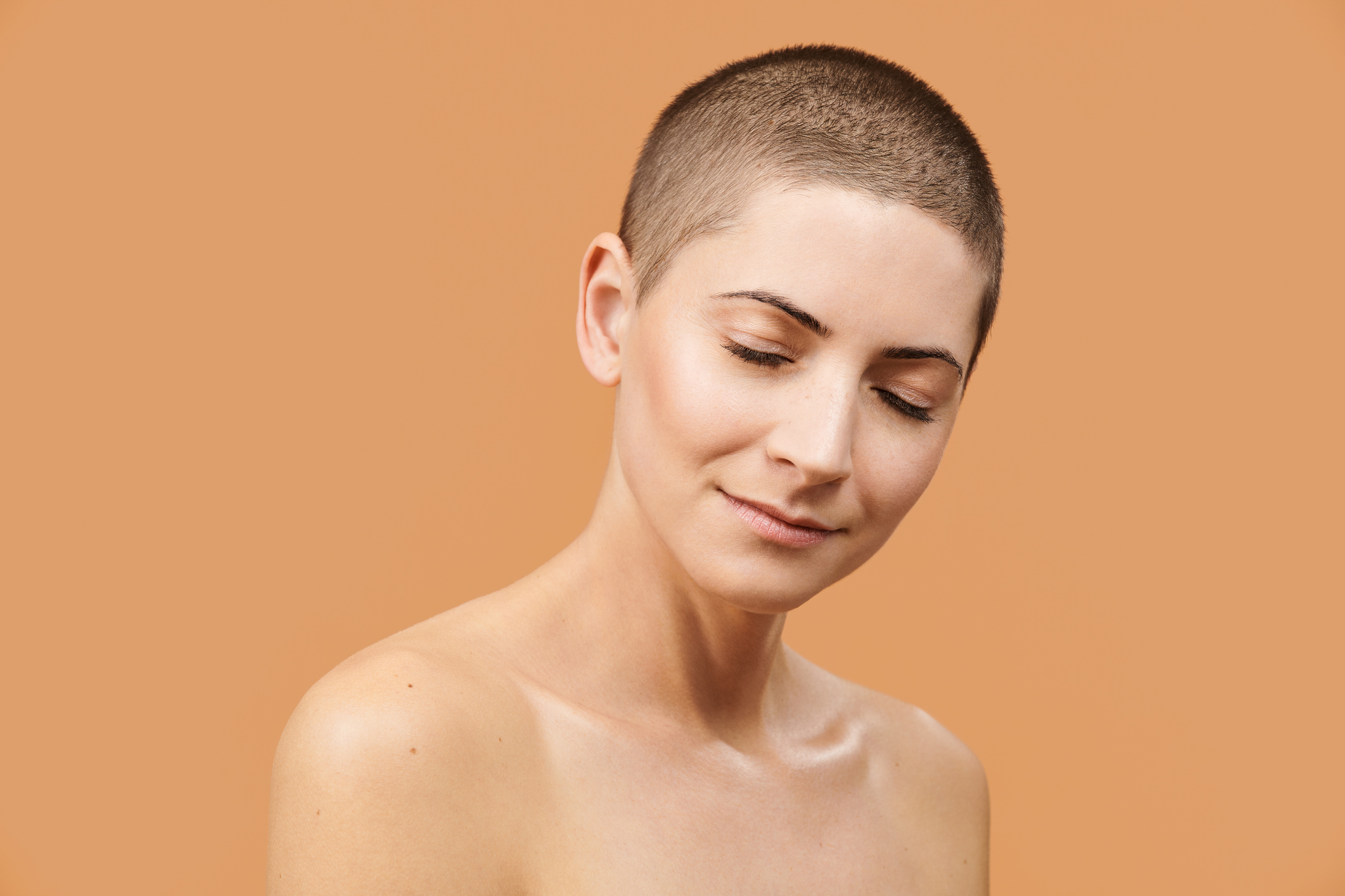 Beautiful mid 30s woman with closed eyes and peaceful facial expression. Photo of attractive caucasian woman with perfect skin on beige background. Youth and Beauty concept.